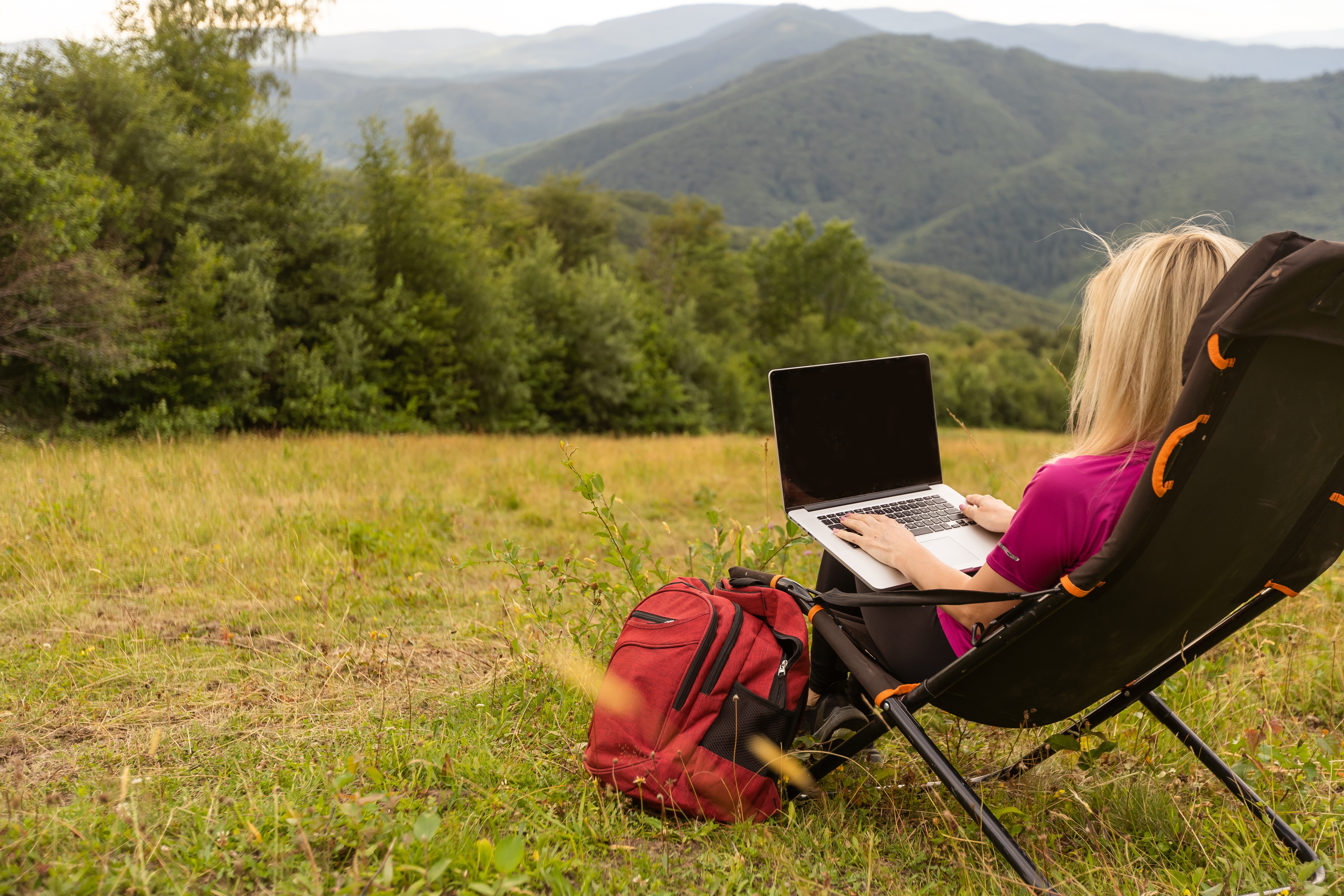 Woman working remotely in the mountains — building a direct booking strategy for her short-term rental